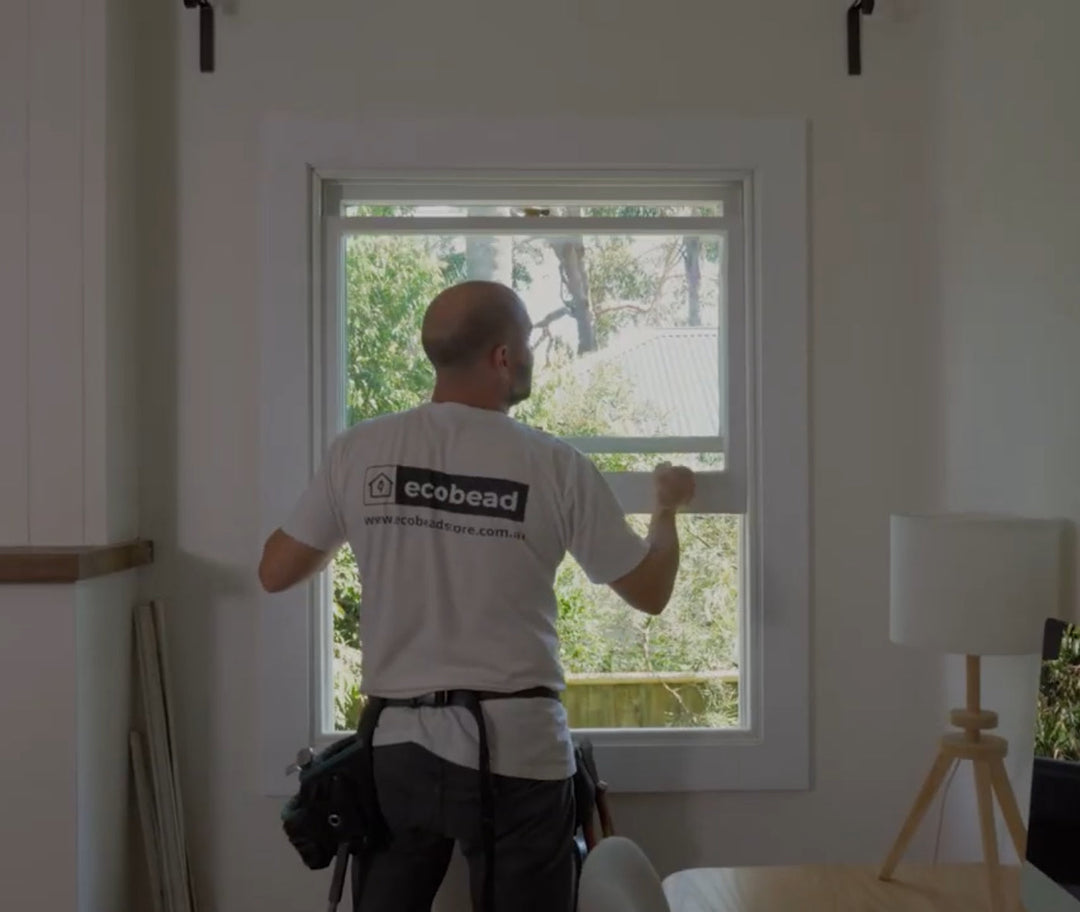Tradesperson draught proofing a double hung sash window
